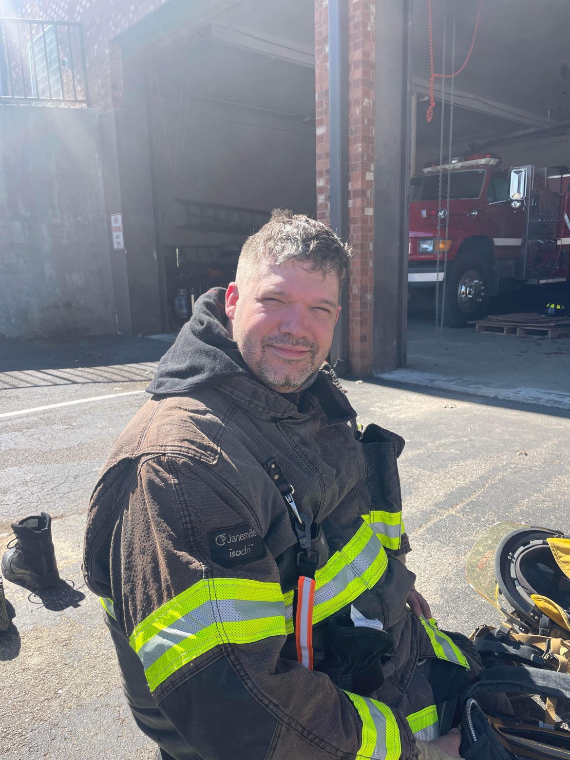 Firefighter seated in turnout gear outside a station