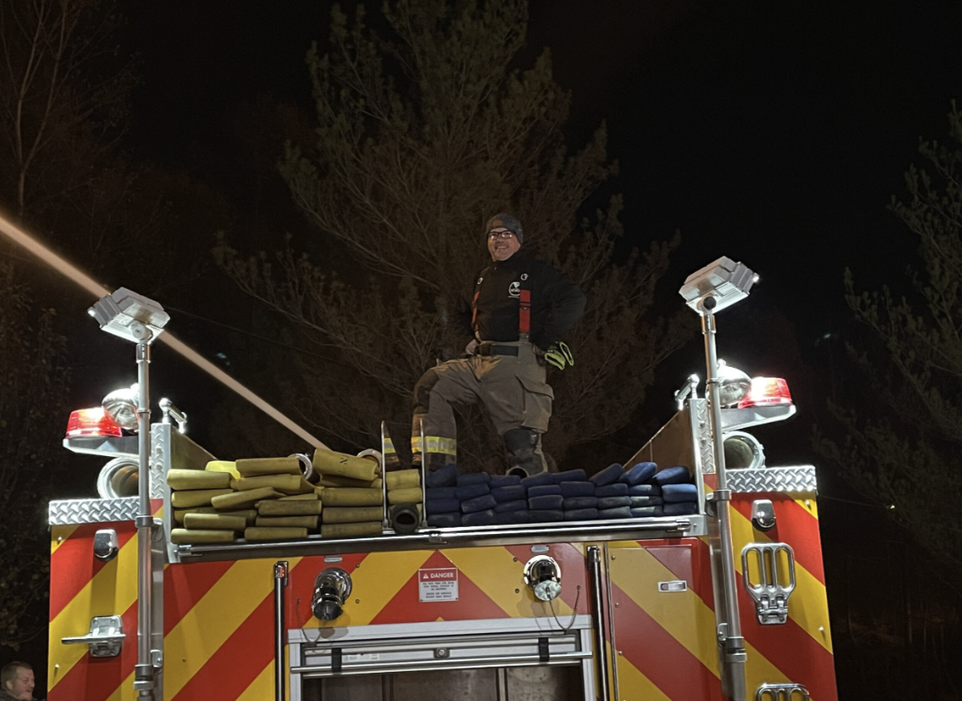 Responder standing on top of apparatus at night