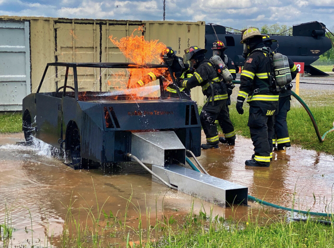 Vehicle fire training exercise with firefighters operating hose line